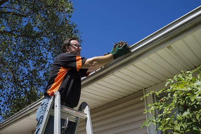 roofing technician replacing a rusted and leaking gutter in Earlham